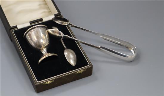 A pair of William IV silver fiddle pattern sugar tongs and a George V silver egg cup and spoon (cased) (3)